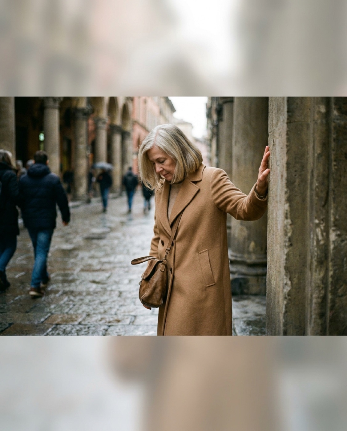 Donna sotto i portici, una mano appoggiata a una colonna, aspetta che passi il giro