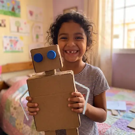 A girl proudly shows her cardboard robot