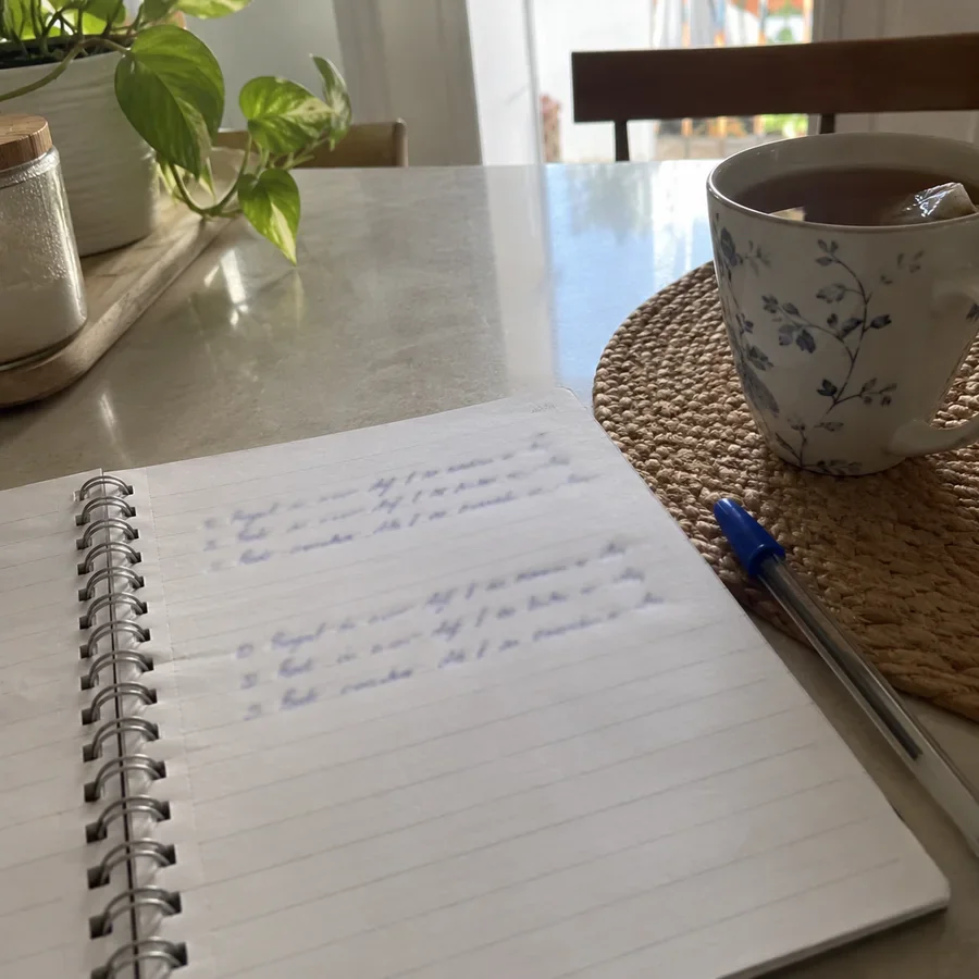 Cuaderno con el Método 369 escrito a mano y una taza de té