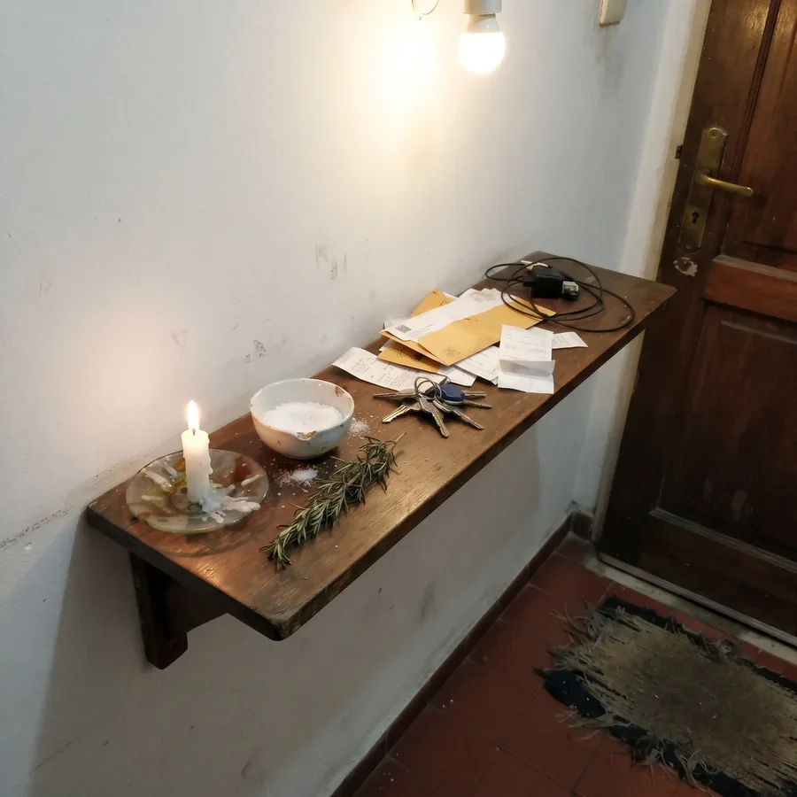Vela encendida, bowl de sal gruesa y romero en el estante de la entrada