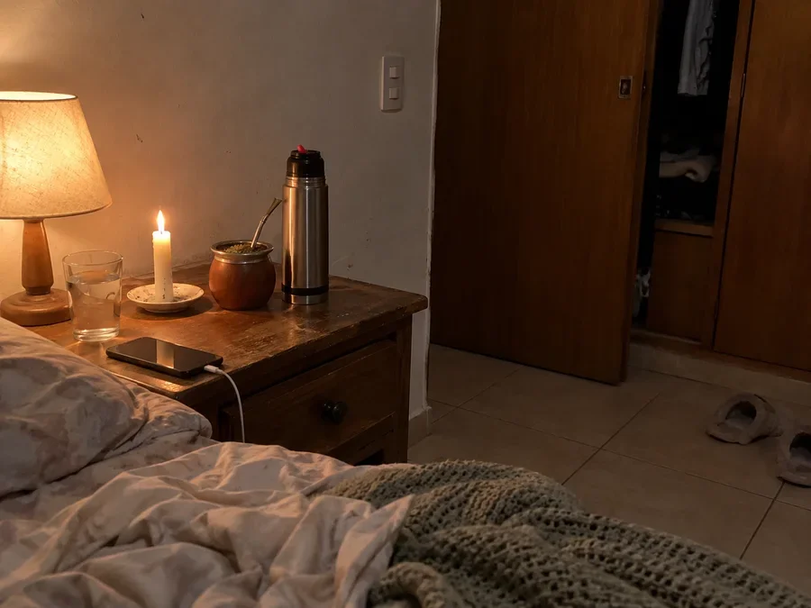 Dormitorio con una vela encendida, un mate y una manta sobre la cama