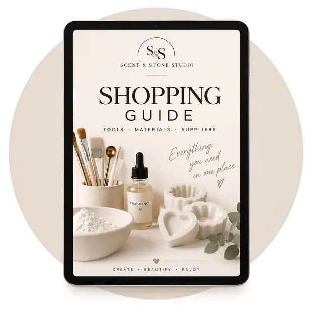 Portada de la Guía internacional de materiales y compras de Scent & Stone Studio en una tableta, con pinceles, aceite de fragancia, escayola en polvo y moldes de corazón y flor
